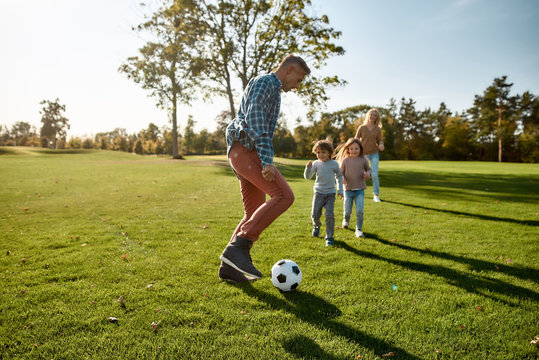 A Nurturing And Creative World. Happy Family Playing With A Ball On Meadow