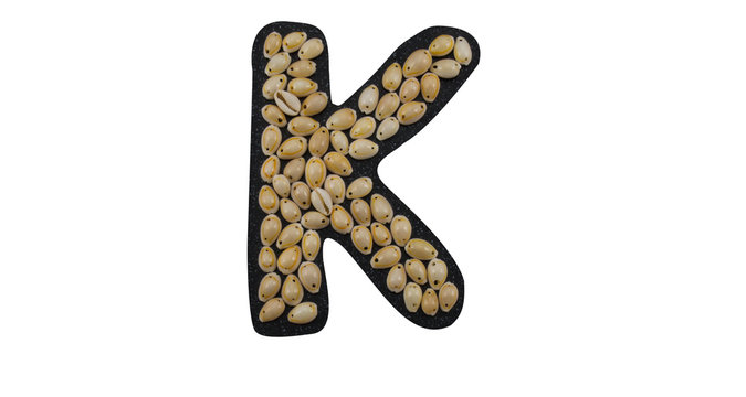 Isolated Font English or Latin Letter K or Russian letter К made of seashell on black granite on white background
