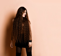 Woman with long hair, in brown turtleneck, short skirt, nylon tights, boots. Smiling, posing on...