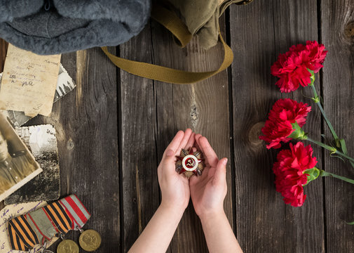 Victory Day.The may 9 celebrations.The girl holds her grandfather's Order of the red Star.Red carnations, St. George ribbon, letters and old photos on a wooden background.Memorial day.Greeting card
