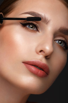 Beautiful girl with sexy lips and classic makeup with cosmetic mascara brush in hand. Beauty face.