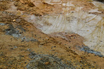 Texture of a dirty bad dirt road dirt road with puddles and clay drying mud with cracks and ruts. Off-road. The background
