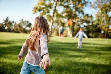 There is no better gift than a family. Little girl playing frisbee with her family in the park on a...