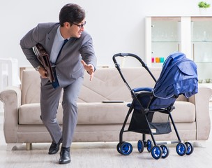 Businessman looking after newborn baby at home and teleworking