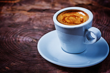 little white ceramic cup with coffee standing on saucer
