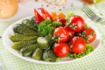 Assorted pickles on a plate. Tomato, cucumber, pepper, garlic.