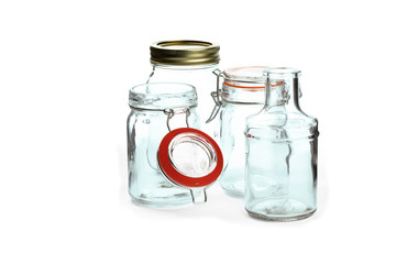 a collection of glass jars with lids and a bottle isolated on white