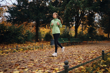 Obraz premium Beautiful sporty girl thoughtfully running around cozy autumn park