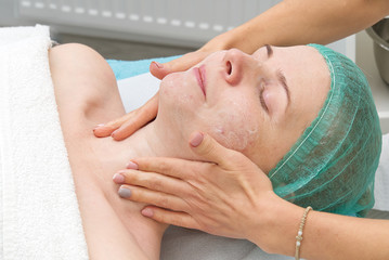 Beautician applies a natural moisturizing mask to the face of a young beautiful woman. Anti-aging mask and wrinkles for problem skin. Cosmetology concept. The cosmetologist performs the procedure to