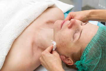 Beautician applies a natural moisturizing mask to the face of a young beautiful woman. Anti-aging mask and wrinkles for problem skin. Cosmetology concept. The cosmetologist performs the procedure to