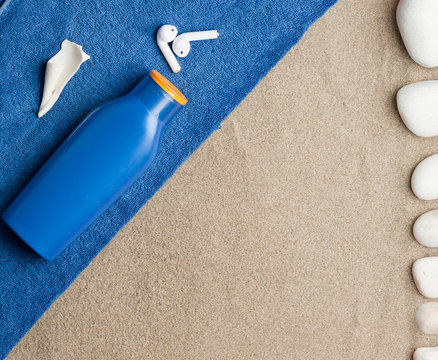 beach set with zul towel, cream boat, conch shell, sand and stone headphones