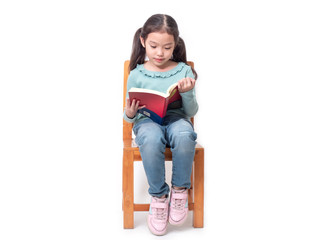 Asian little cute girl 6 years old sitting on wood chair and reading the book. Preschool lovely kid...