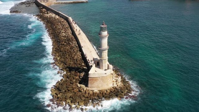 Aerial drone video of iconic Venetian lighthouse in the entrance of picturesque old port of Chania with beautiful colours, Crete island, Greece. Lighthouse in Chania. Lighthouse of the city of Chania.
