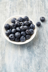 Bilberries on bright wooden background. Concept for healthy nutrition. Copy space.