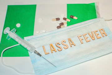Nigerian flag under words Lassa fever outbreak concept. protective breathing mask and syringe....