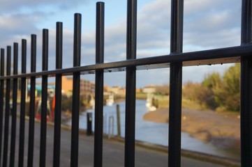 Black steel railing with blurred background view of river