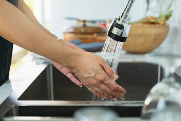 Mid section of woman washing hands in the kitchen. Woman Washing Her Hands. Close up of chef washing her hands in commercial kitchen.