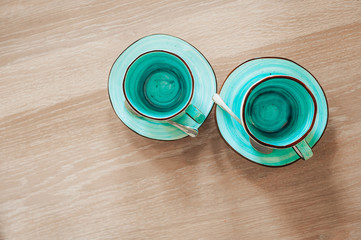 Two very beautiful empty cups of blue and mint color with saucers on a rough wooden table. top view on romantic intimate dinner for two persons