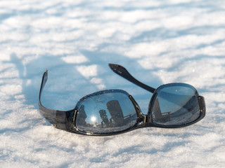 sunglasses in a snow drift in winter with reflection of the sun