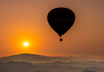 Silhouette of hot air balloon over forest  and mountain in sunset, sunrise sky background