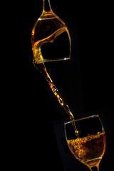Pour the orange water from the glass into the crystal wine glass, spread it closely on a black background.