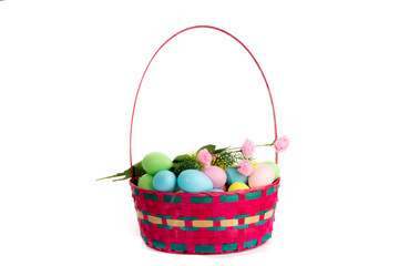 a wicker basket of colorful Easter eggs isolated on white
