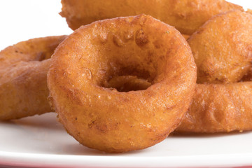 closeup macro view of jumbo onion rings on a white plate isolated on white