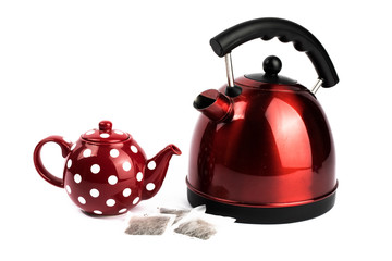 a red electric kettle and a red and white polka dot teapot with tea bags isolated on white 