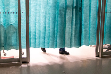 feet behind blue, green curtain in hospital