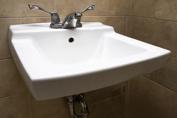 Fototapeta premium a white bathroom sink with large hot and cold water taps easy for people with a handicap to operate