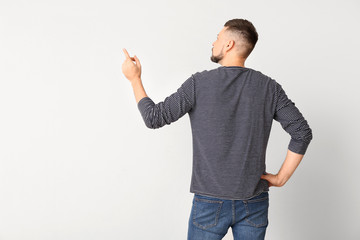 Man pointing at something on light background