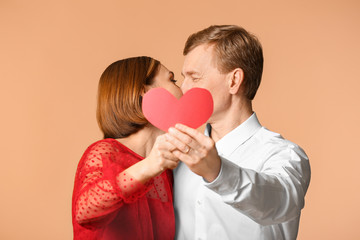 Fototapeta na wymiar Portrait of beautiful couple with red heart on color background