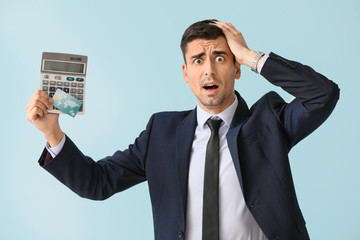 Afraid male bank manager with credit card and calculator on light background