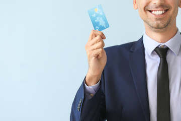 Male bank manager with credit card on light background