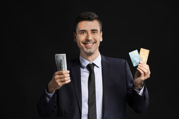 Male bank manager with credit cards and money on dark background