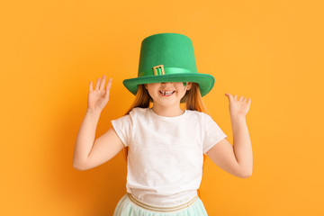 Funny little girl on color background. St. Patrick's Day celebration