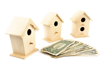 a row of bird houses around a pile of dollar bills representing real estate investment isolated on white