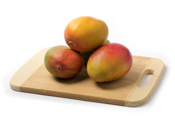 ripe natural looking mangoes on a white table top