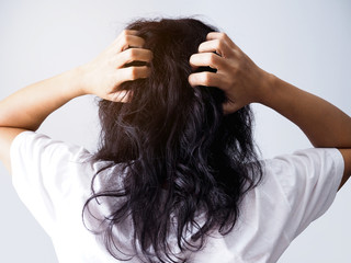 Asian woman with long black hair scratching head from itching and having messy hair.