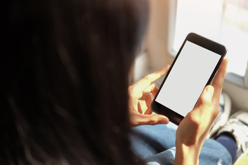 Cropped shot view of woman hands holding smart phone with blank copy space screen for your text message or information content, female reading text message on cell telephone during in urban setting. 