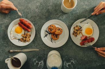 Breakfast set of sausages fried eggs and mushroom with fresh milk and cookies served on the table.
