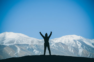 Silhouette of woman hiker stands on the rock in the beautiful mountains view of snowy Tso Moriri Lake in Leh Ladakh india, success concept