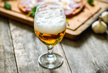 Freshly brewed beer and pepperoni pizza in bar. Selective focus. Shallow depth of field.