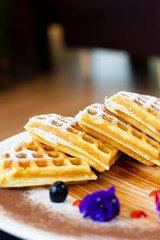 Homemade waffles with berries in plate on table at cafe.
