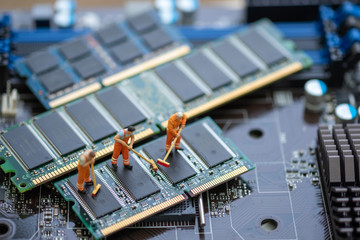 Miniature People: Worker cleaning professional repairman holding a cleaning brush inside old personal computer. Ram cleaning and maintenance concept, close up view.