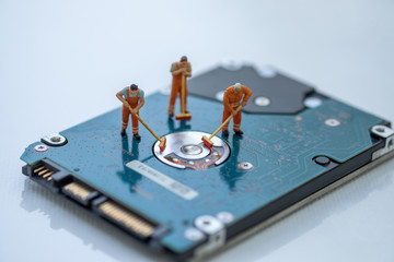 Miniature People: Worker cleaning professional repairman holding a cleaning brush inside old personal computer. Harddisk cleaning and maintenance concept, close up view.
