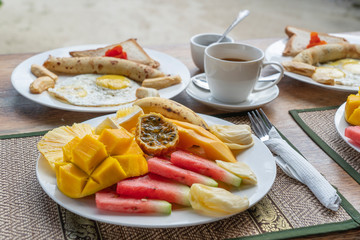 Tropical breakfast of fruit, coffee and scrambled eggs and banana pancake for two on the beach near sea