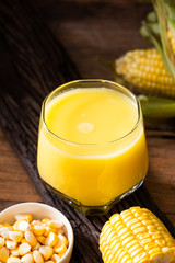 Fresh sweet corn juice (corn milk) and corn on wood background