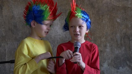 Two crying boys received latest smartphone models as gift from their parents. children turned on music, dressed in punk Iroquois carnival wigs and sang karaoke in front of microphone on stand