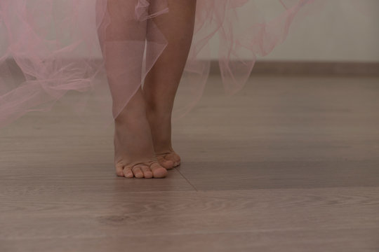 little girl tiptoe legs in a long light pink skirt